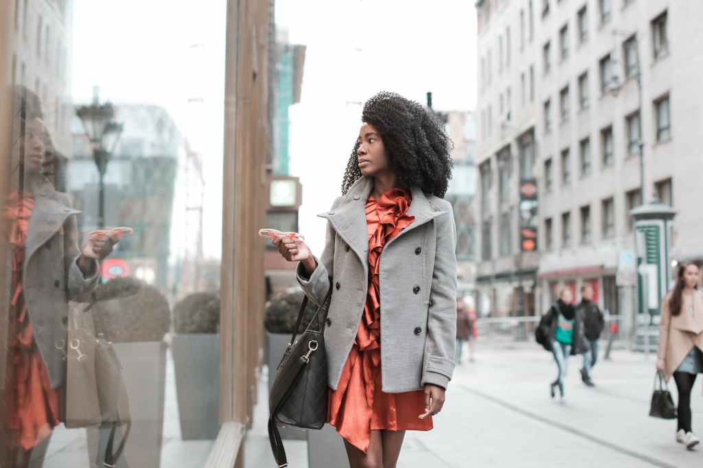 selective focus photo of woman in gray coat walking by store window