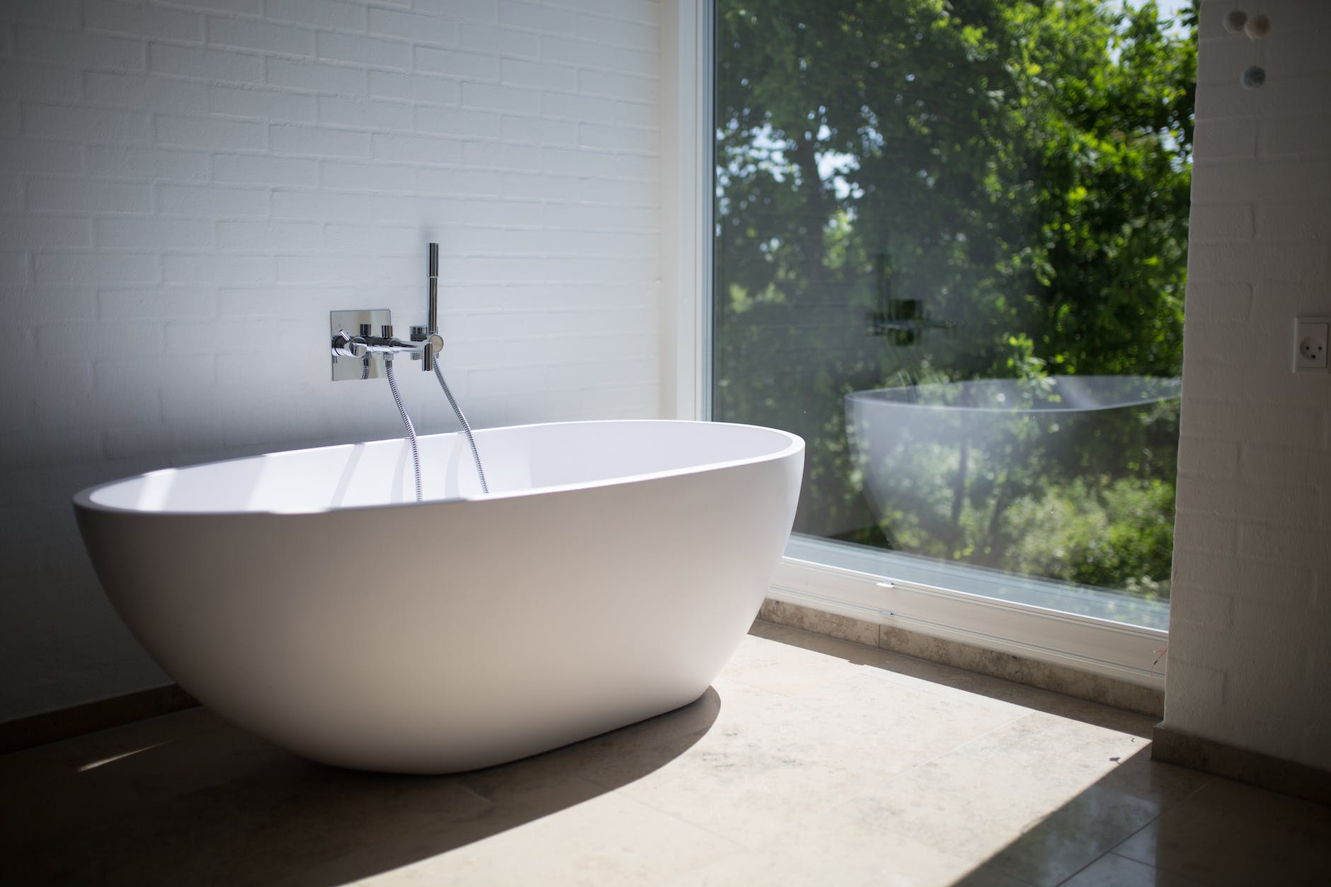 white ceramic bathtub beside clear glass wall
